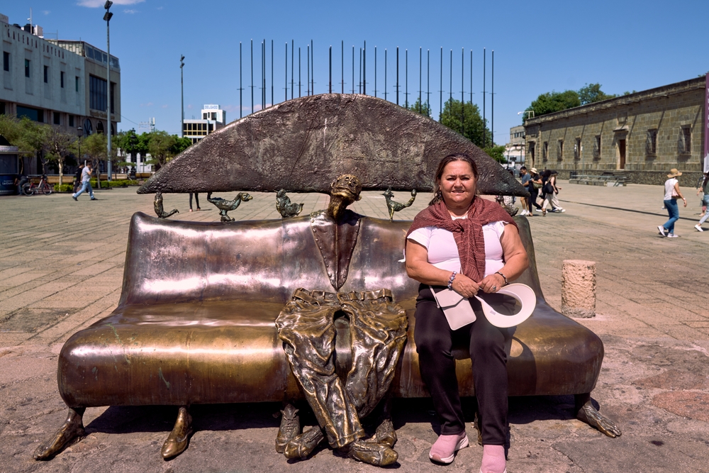 Turista posa sentado en un sillón en el salón de los magos de la plaza iberoamericana de Guadalajara frente al hospicio de Cabañas.