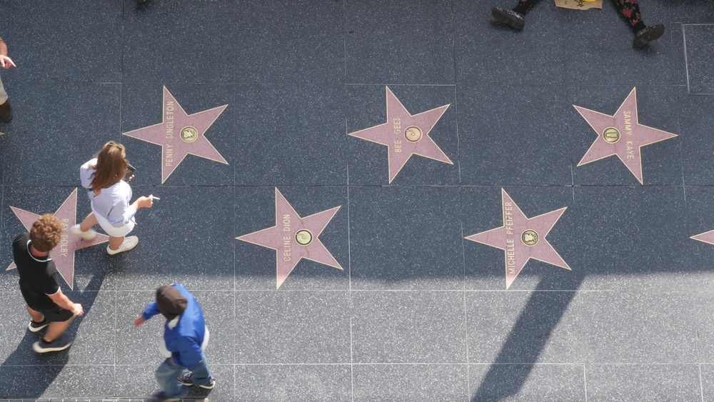 Gente pasea por el Walk Of Fame, con sus baldosas conmemorativas.