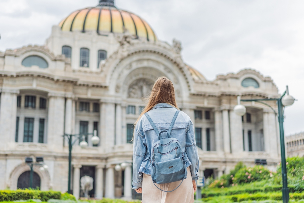 Female tourist standing in front of the Palace of Fine Arts in Mexico City.