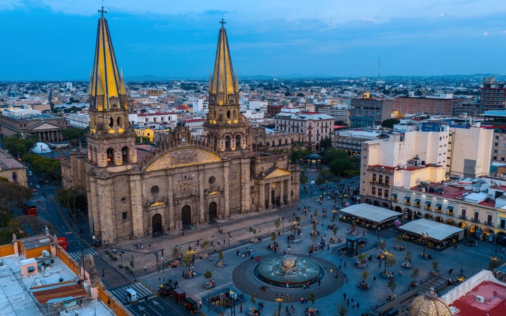 Aerial views of the Guadalajara Cathedral and surrounding plaza at dusk, showcasing the city's historic architecture and lively atmosphere.
