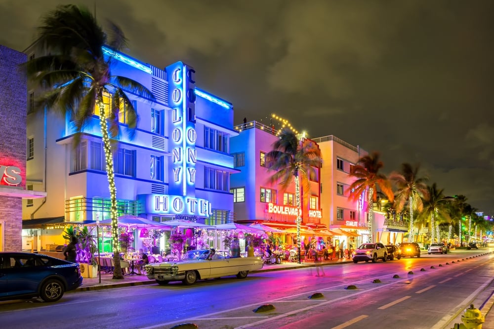 La icónica avenida Ocean Drive de Miami con sus edificios iluminados al anochecer.