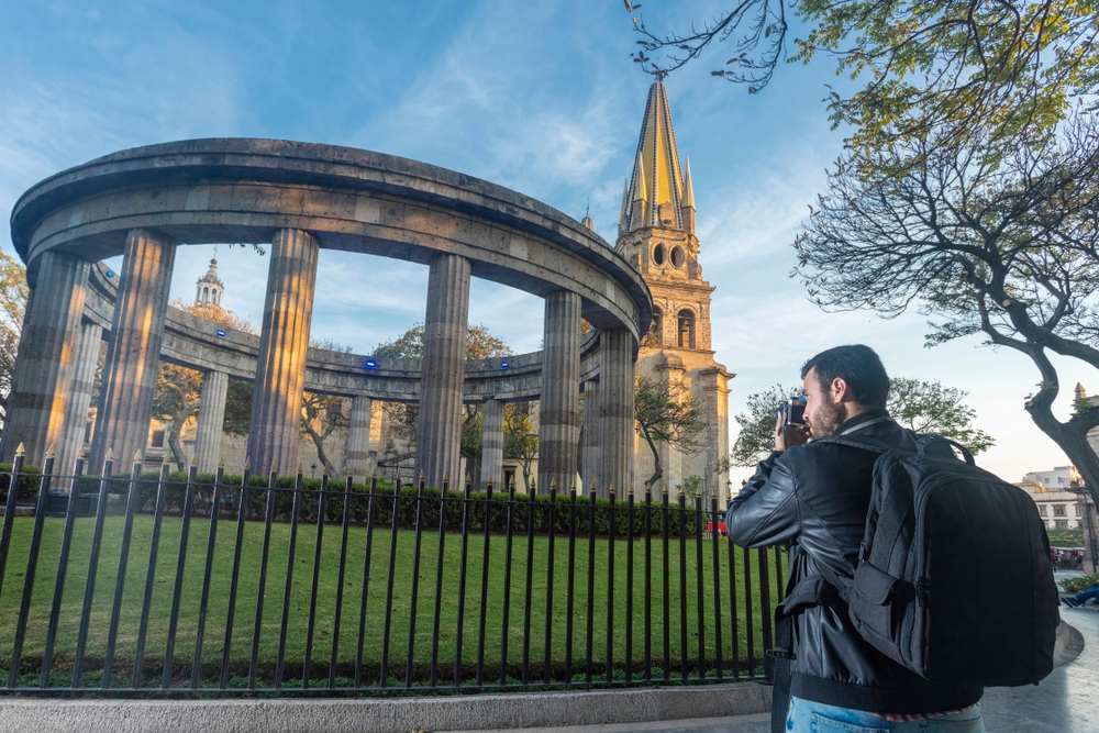 Young tourist photographer taking picture of the Rotunda and Cathedral of Guadalajara, Jalisco, Mexico.