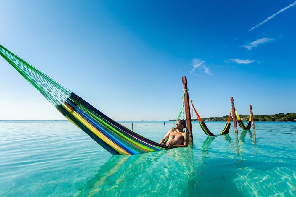 A man relaxing on a hanging hammock inside the ocean.