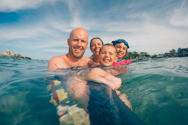 Familia sonriendo mientras nada en el mar durante sus vacaciones.