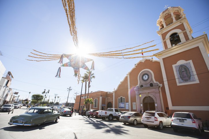 Iglesia tradicional de Mexicali decorada con piñatas en una calle céntrica durante festividades.