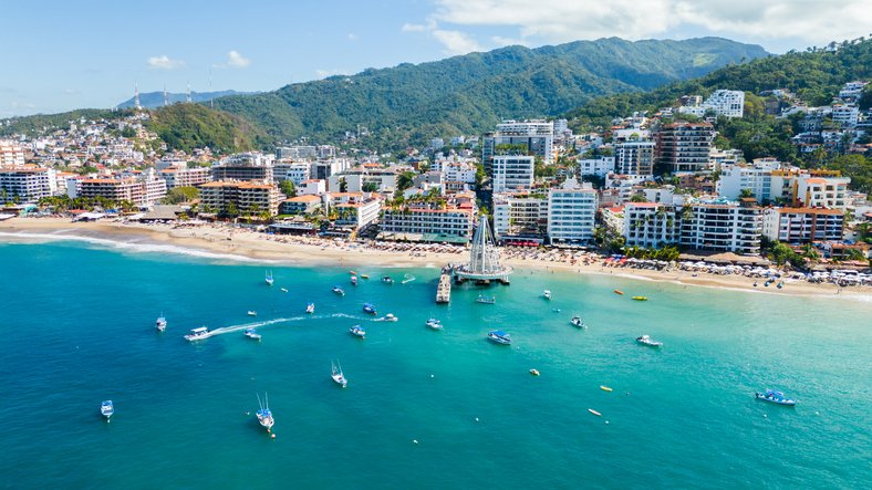 Vista panorámica de Puerto Vallarta con el muelle, la playa y la Sierra Madre al fondo.