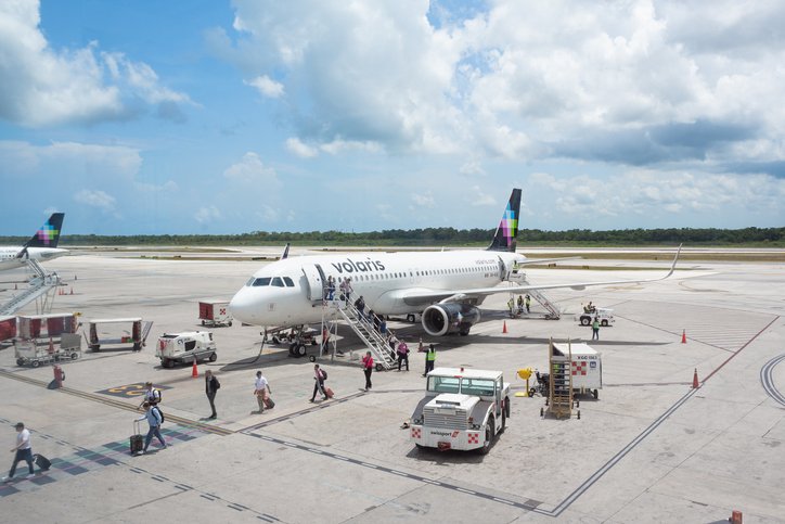 Avión de Volaris estacionado en pista con pasajeros abordando en el aeropuerto de Puerto Vallarta.