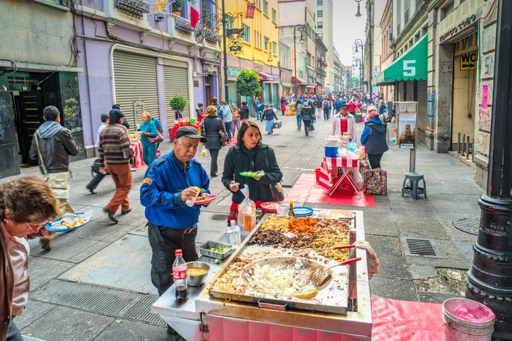 Puesto de comida callejera en el Centro Histórico de CDMX, con personas disfrutando antojitos.