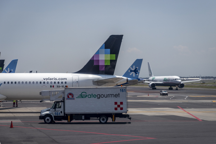 Ala trasera de un avión de Volaris estacionado en el aeropuerto junto a otros aviones.