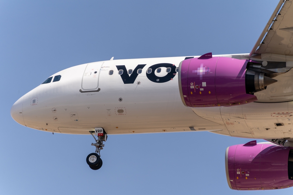 Parte delantera de un avión de Volaris aterrizando desde el cielo.