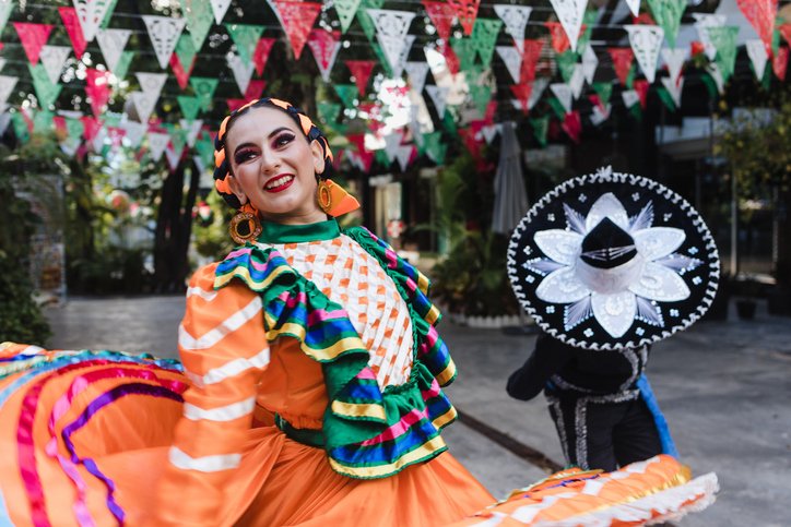 A couple of mariachi dancers dressed in colonial costumes performing a dance in the streets.