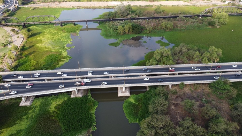Vista aérea del río Culiacán, atravesado por autopistas y tranvías modernos.