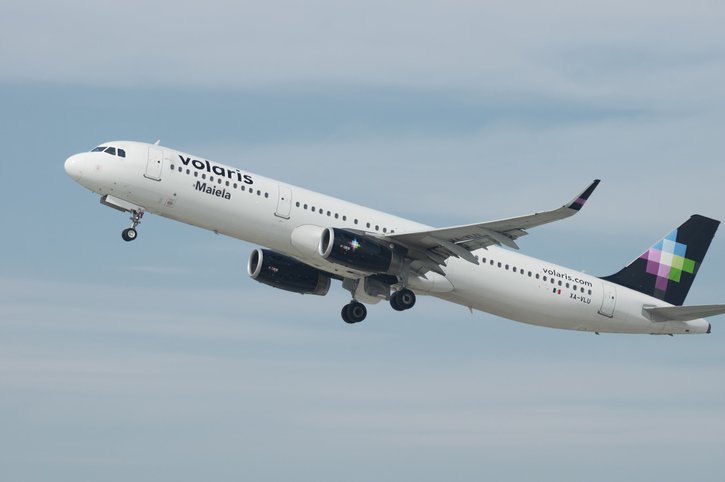 Volaris airbus “Maiela” flying across a cloudy sky.