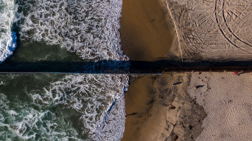Vista aérea del muro fronterizo atravesando las playas de Tijuana.