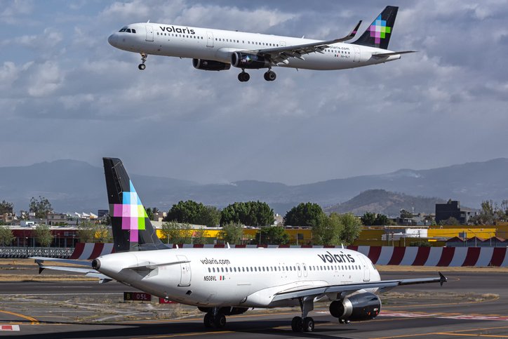 Two Volaris airbuses landing and departing at the airport.