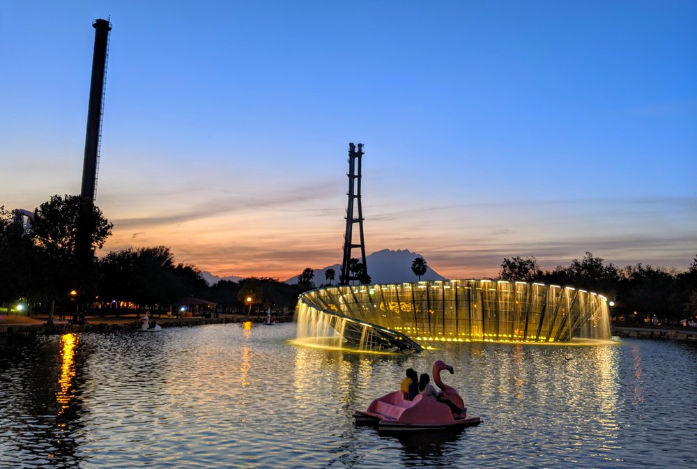People riding a love boat across the lake at Paseo Santa LucÃa at night.