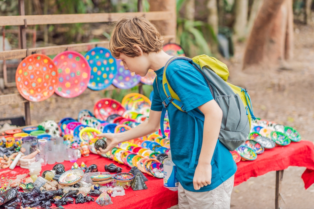 Niño comprando recuerdos mexicanos en un mercado de artesanías de Cancún.
