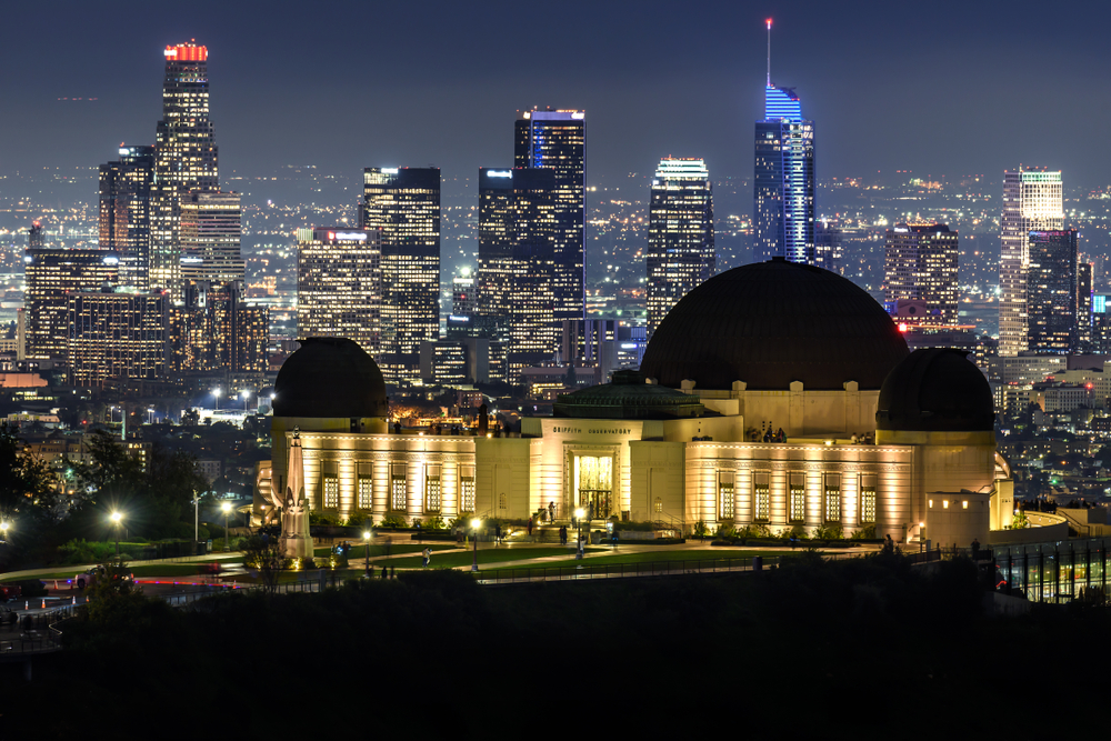 Vista panorámica del Observatorio Griffith y rascacielos de Los Ángeles iluminados en la noche.