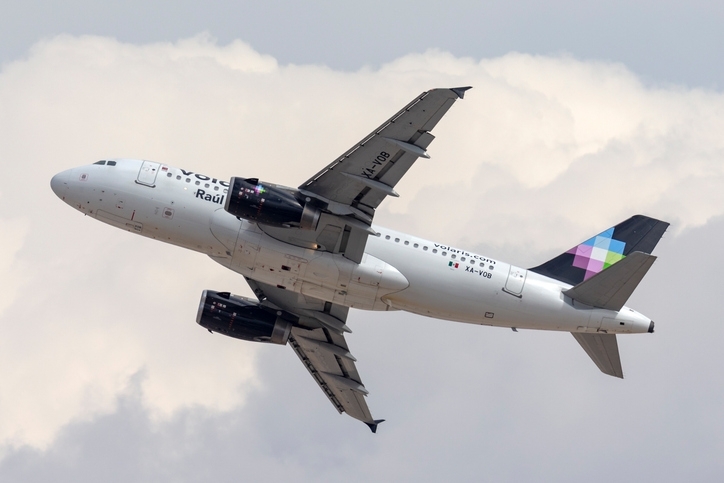 Avión de Volaris visto desde abajo, en un cielo nublado.