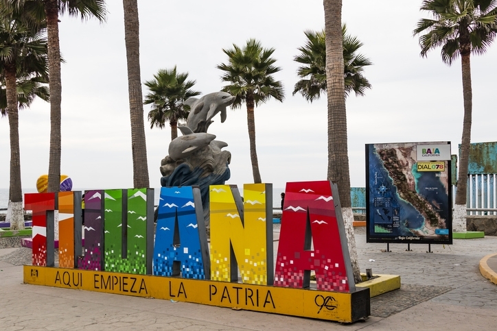 Colorido cartel de Tijuana cerca de sus playas, en la pared de frontera internacional.