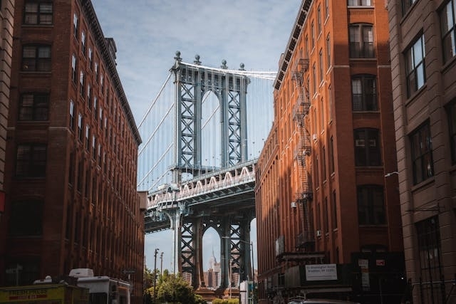 Vista del puente de Manhattan en Nueva York enmarcado entre edificios de ladrillo en el vecindario de Dumbo, Brooklyn.