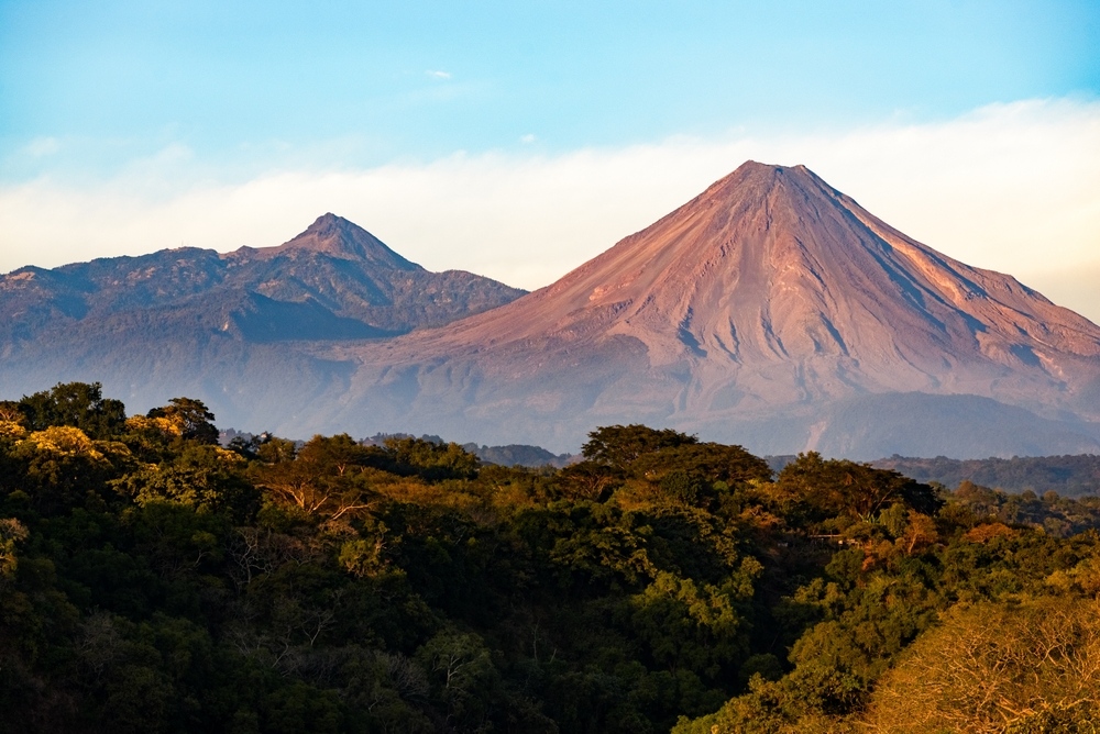 Vista panorámica de los dos volcanes de Colima, el Volcán de Fuego y el Nevado de Colima, durante el atardecer.