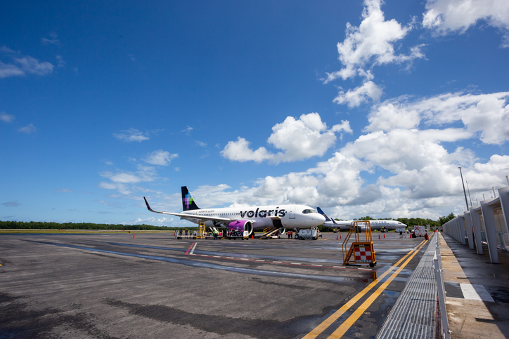 Avión de Volaris en la pista del estacionamiento de Cancún.