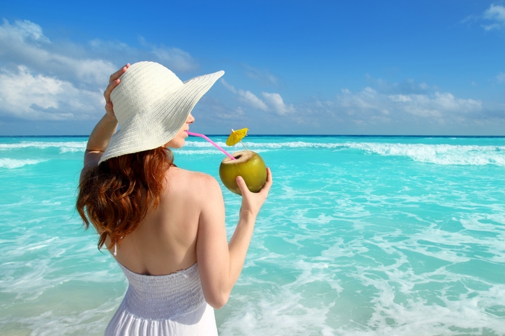 A woman drinking a cocktail by the sea.