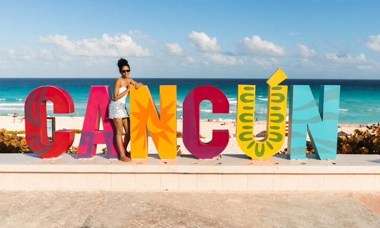 Woman posing next to Cancun’s sign.
