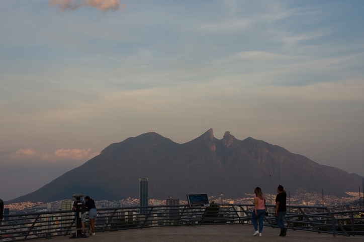 People admiring the Cerro de la Silla from a city viewpoint in Monterrey.