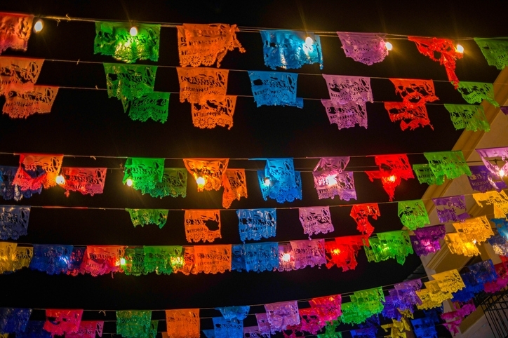 Colorful classic Mexican flags hanging from the ceilings in the street.