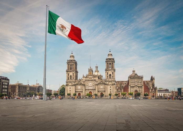 A big Mexican flag waves in front of the Metropolitan Cathedral in Mexico City.