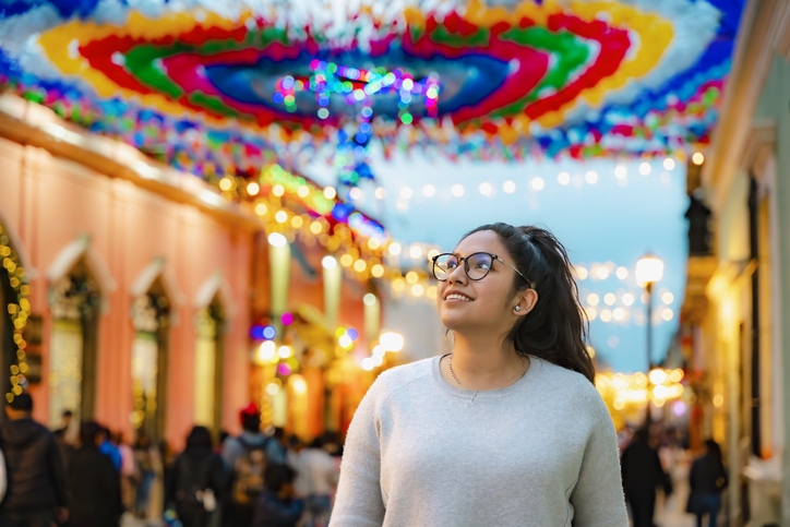 Mujer caminando por una calle del centro de Oaxaca decorada con luces y papel picado.