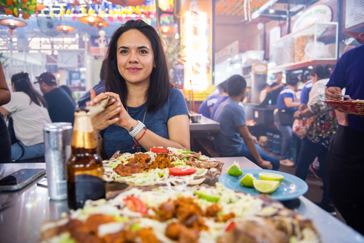 A female traveler enjoying Tlayuda at a street market.