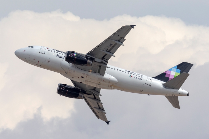 Volaris plane flying through a cloudy sky.