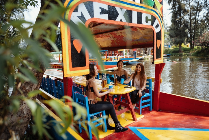 Tres amigas viajeras disfrutando cervezas en un bote de Xochimilco.