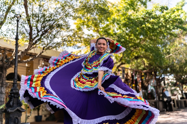 Mujer jóven danzando con vestido tradicional mexicano.