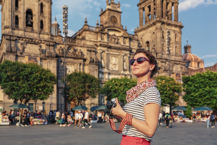 Turista sacando fotos frente a la plaza principal del Zócalo y la Catedral Metropolitana