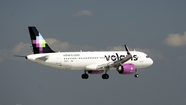 Avión de Volaris iniciando el aterrizaje sobre un cielo ligeramente nublado.